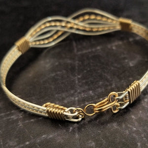 Symbolizes enduring love and commitment. Handcrafted in strands of both smooth and hand twisted precious metals. The bracelet can be locked for a beautifully discreet symbol of submission or ownership, or it can be created as a traditional bracelet.Sterling and Yellow 14k Gold Filled.