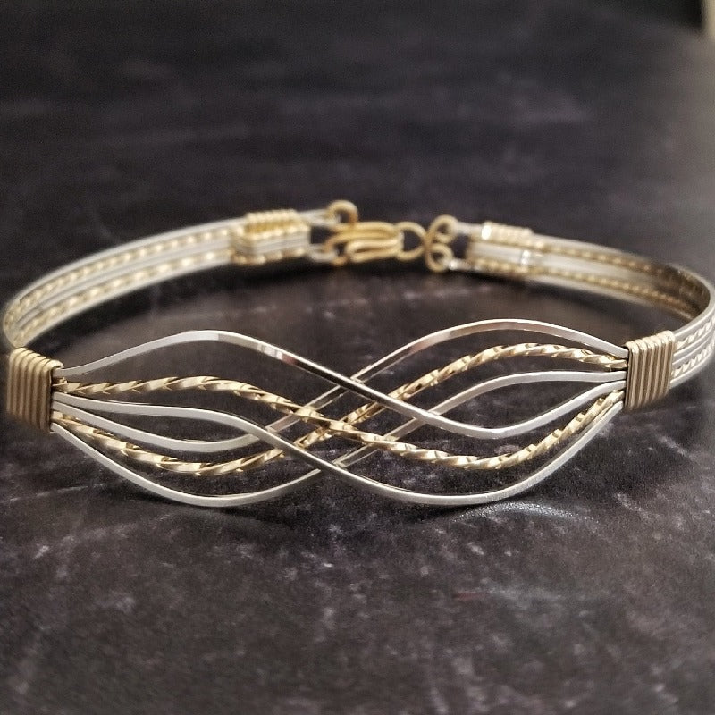 Symbolizes enduring love and commitment. Handcrafted in strands of both smooth and hand twisted precious metals. The bracelet can be locked for a beautifully discreet symbol of submission or ownership, or it can be created as a traditional bracelet.Sterling and Yellow 14k Gold Filled.