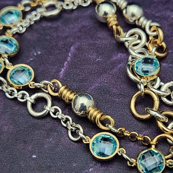 A locking submissive kitten bell handcrafted with all the grace and discretion that My Secret Heart is known for. The asymmetrical design features aquamarine, securely wrapped and incorporated into both steering and gold filled chains and links. 