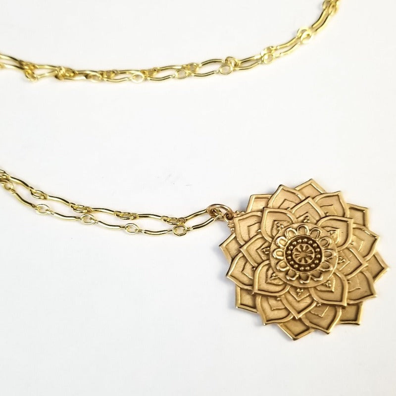 This exquisite bronze Mandala pendant features a lotus blossom created with multiple overlapping petals, each intricately textured. Oxidized to enrich the beautiful details.   Smooth and polished back.   The curving bar chain blends perfectly, adding a delicate and graceful flair. 