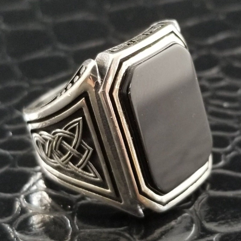 A signet style ring in sterling silver with an octagon-cut black onyx cabochon. Beautiful details include Celtic knots and beading on the top and bottom edges of the bezel.