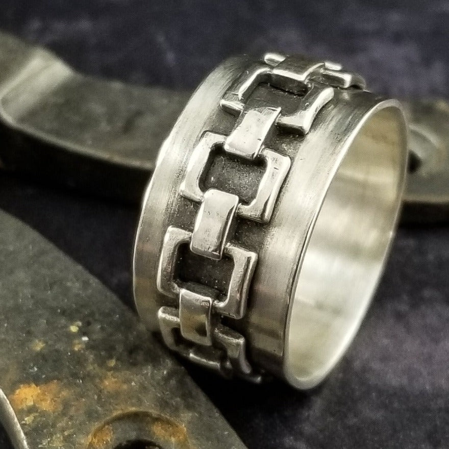 The Chain Link Ring pays homage to the BDSM bondage lifestyle. A handcrafted band of smooth, hefty silver is embellished with a chain motif. Very substantial, this high-quality artisan ring will be enjoyed for a lifetime.   