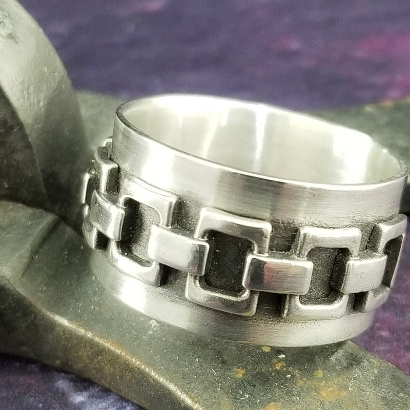 The Chain Link Ring pays homage to the BDSM bondage lifestyle. A handcrafted band of smooth, hefty silver is embellished with a chain motif. Very substantial, this high-quality artisan ring will be enjoyed for a lifetime.   