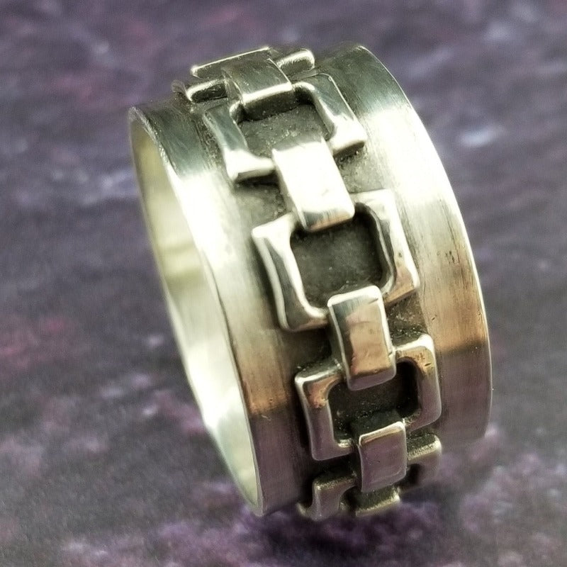 The Chain Link Ring pays homage to the BDSM bondage lifestyle. A handcrafted band of smooth, hefty silver is embellished with a chain motif. Very substantial, this high-quality artisan ring will be enjoyed for a lifetime.   