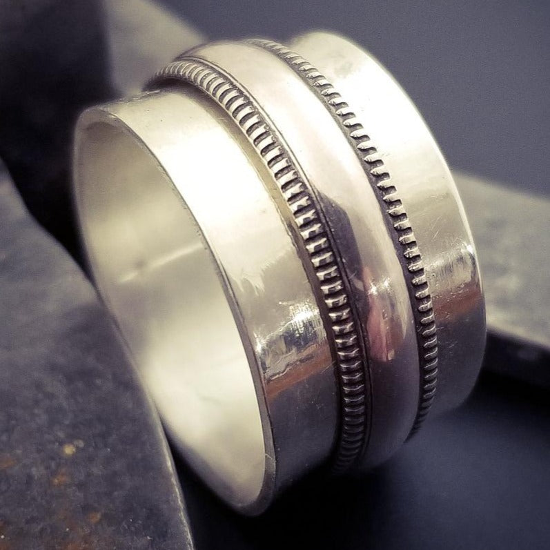 From our JANUS COLLETION, this ring is the perfect companion to the submissive collars and handcuffs. Very substantial, this high-quality artisan ring will be enjoyed for a lifetime. A spinning band of the Janus pattern in sterling on a hefty band of sterling silver. All handcrafted.