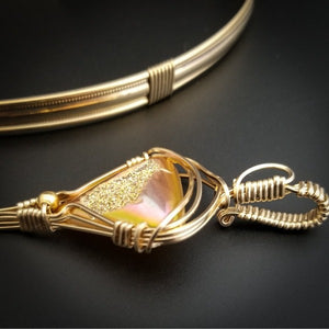 An incredibly luxurious look for a submissive collar. A triangular cut Gold Window Druzy is encased in a gold wire wrapped pendant that can be worn alone or slid onto most of our submissive collars. Featuring stunning open lattice work and a 14k gold filled chain that can be worn with a traditional clasp, or locked with a lock and key.