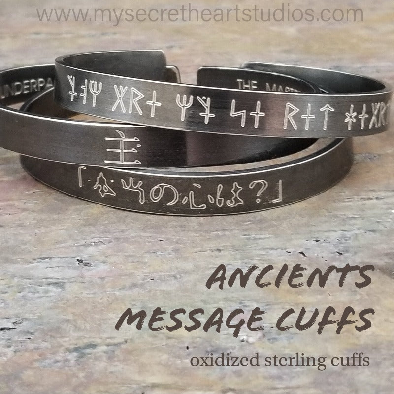 Share a secret. Ancient looking fonts create unique cuffs with a secret message. The outside inscription is Kanji symbols. Traditional Cuff with gap. All Sterling Silver, heavily oxidized. Message: You Are My Secret Heart