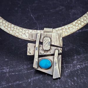Add some personality to your collar. This collar slide is handcrafted in sterling silver with a bezel set Turquoise cabochon. A very Asian inspired asymmetrical design. The pendant comes with a sterling silver chain, but the unique clip design allows you to also clip the pendant over your own beaded necklaces for a dramatic and unique style.
