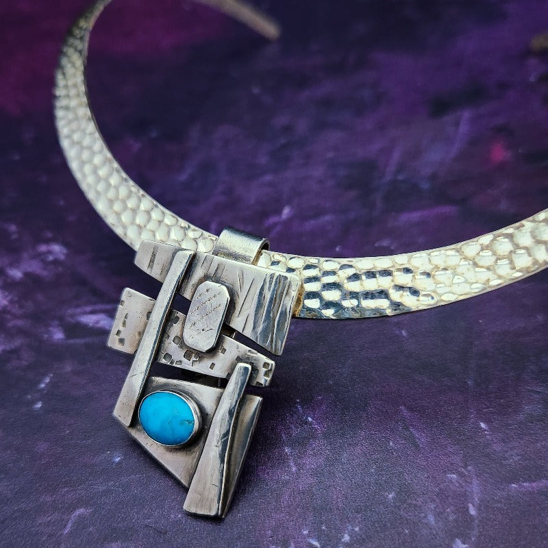 Add some personality to your collar. This collar slide is handcrafted in sterling silver with a bezel set Turquoise cabochon. A very Asian inspired asymmetrical design. The pendant comes with a sterling silver chain, but the unique clip design allows you to also clip the pendant over your own beaded necklaces for a dramatic and unique style.