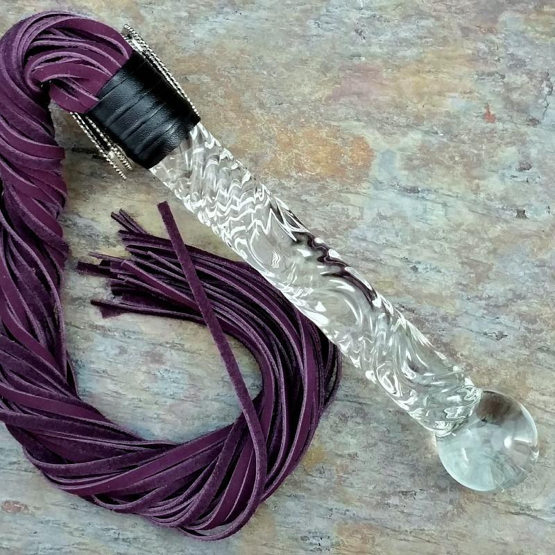 Get your kink on with this BDSM Flogger in Purple Leather and Glass. With a whip on one end and a glass dildo on the other, you’ll have the perfect balance between pleasure and pain! Can be Monogrammed / Engraved. By My Secret Heart Studios