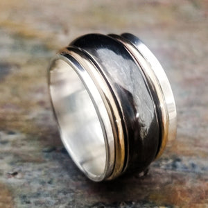 Spinning bands of sterling silver and 14K gold-filled wire encircles a wide, hefty band of sterling silver. Goes beautifully with almost all of our submissive collars and handcuffs. Very substantial, this high-quality artisan ring will be enjoyed for a lifetime.
