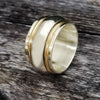 Spinning bands of sterling silver and 14K gold-filled wire encircles a wide, hefty band of sterling silver. Goes beautifully with almost all of our submissive collars and handcuffs. Very substantial, this high-quality artisan ring will be enjoyed for a lifetime.