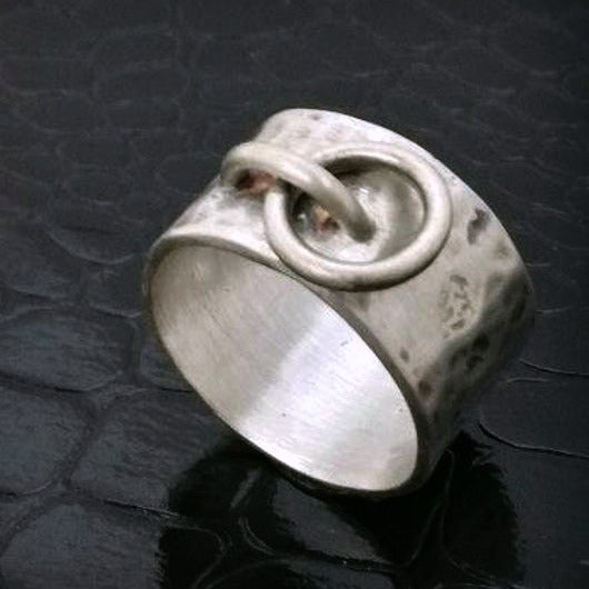 Styled after the ring described in the classic "The Story of O" novel.  This style features a hammered band with dark patina added to emphasize the texture. The wide band averages approx. 11-12 mm wide.