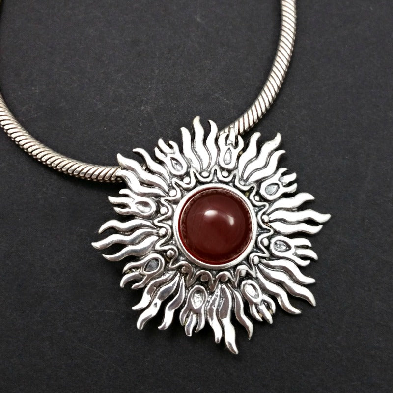Dramatic Fire pendant with hand set with a  gemstone cabochon in your choice of black onyx, carnelian or moonstone. The pendant is sterling silver, the bail is silver plated. Can be worn as a pendant on a chain, or slide onto most all or our artisan collars.