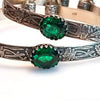 These artisan BDSM submissive handcuff bracelets are hand crafted in a classic floral pattern of sterling silver with faceted emerald gemstones.