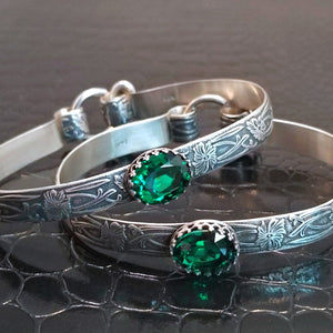 These artisan BDSM submissive handcuff bracelets are hand crafted in a classic floral pattern of sterling silver with faceted emerald gemstones.