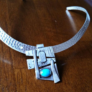 Add some personality to your collar. This collar slide is handcrafted in sterling silver with a bezel set Turquoise cabochon. A very Asian inspired asymmetrical design. The pendant comes with a sterling silver chain, but the unique clip design allows you to also clip the pendant over your own beaded necklaces for a dramatic and unique style.