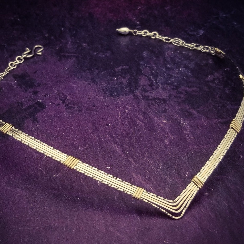 A beautiful symbol of your D/s dynamic, this contemporary V Style Locking BDSM submissive collar is hand crafted in mixed precious metals of sterling silver and gold. As strong and beautiful as the submissive’s heart, this high-quality artisan collar is made to last and will be the foundation of your private collection