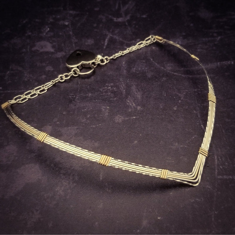 A beautiful symbol of your D/s dynamic, this contemporary V Style Locking BDSM submissive collar is hand crafted in mixed precious metals of sterling silver and gold. As strong and beautiful as the submissive’s heart, this high-quality artisan collar is made to last and will be the foundation of your private collection